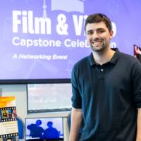Film student smiling and standing in front of his booth